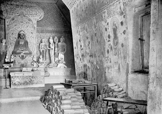 Aurel Stein et la grotte 16 avec des manuscrits empilés à côté de l'entrée de la grotte 17 en 1905.
